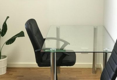 Meeting area with a glass-topped table, leather chairs, and colorful abstract wall art.