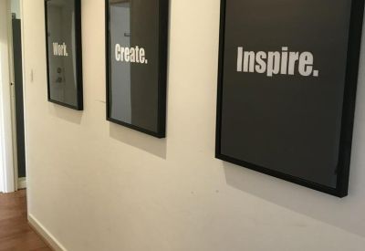 Office corridor featuring three framed motivational posters on a white wall.