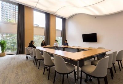 Large boardroom with a U-shaped table, ergonomic chairs, and a unique wavy light fixture.