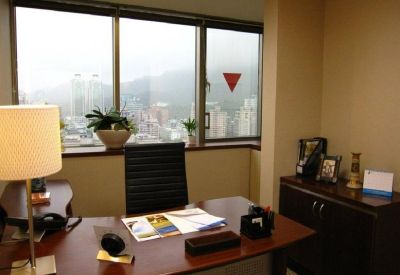 Private office featuring a wooden desk and large windows overlooking the city.