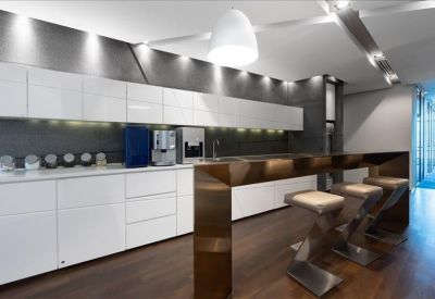 Modern office pantry with white cabinetry, a dark splashback, and breakfast bar with stools.