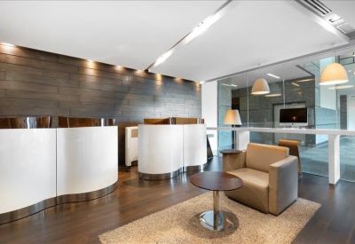 Lounge area featuring white curved reception desks and a comfortable tan armchair on a rug.