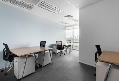Brightly lit open-plan office with three wooden desks and white mobile pedestals.