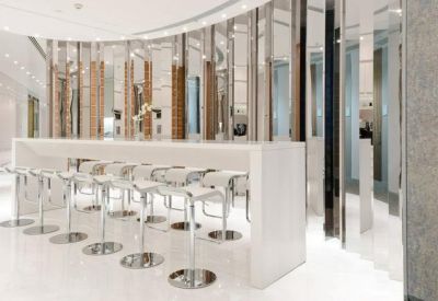 Modern café-style communal seating with white bar stools and mirrored pillars.