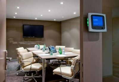 Professional meeting room with a large table, leather chairs, and wall-mounted screen.