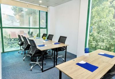 Conference room with tables, chairs, and large green-framed windows.