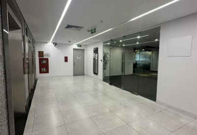 Bright white elevator lobby with large floor tiles and glass entrance doors.