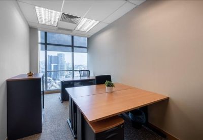 Compact private office featuring two wooden desks and a large window with city views.