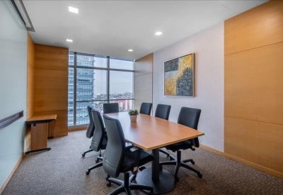 Modern meeting room with a large wooden table, black ergonomic chairs, and city views.