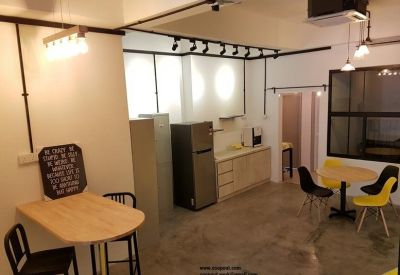 Communal break area with wooden tables, modern chairs, and a small kitchenette.