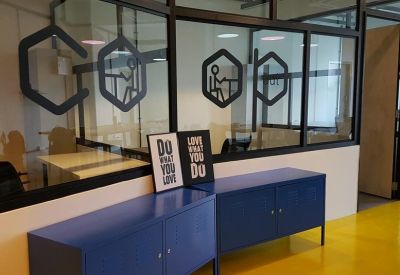 Glass office partition featuring motivational decals and a blue storage cabinet.