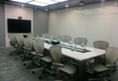 Boardroom with a long table, ergonomic chairs, and a wall-mounted screen.