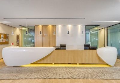 Modern curved white and wood reception desk with warm under-lighting and wood panelled background.