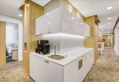 Modern communal kitchen area with sleek white cabinets and warm wood paneling.