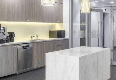 Sleek kitchen breakout area featuring a marble island and wooden cabinetry.