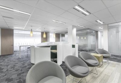 Reception waiting area with modern grey armchairs and curved white pods.