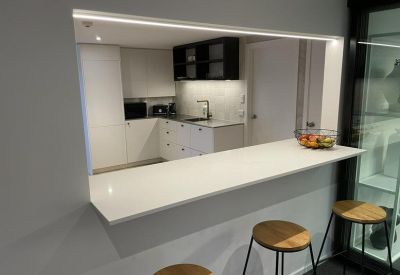 Sleek kitchen breakout area with a white breakfast bar and stools.