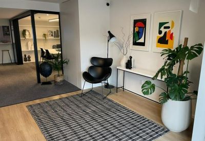 Stylish waiting area featuring a designer chair, abstract art, and a large monstera plant.