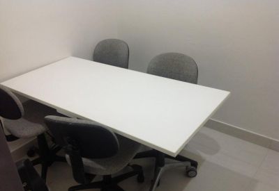 Meeting room with a white rectangular table and four grey upholstered chairs.