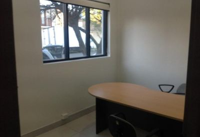 Office workspace showing an L-shaped desk and a window overlooking trees.