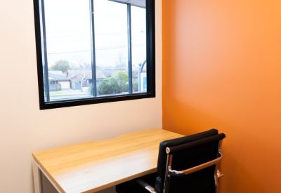 Compact desk setup with an orange wall and views over the local neighborhood.