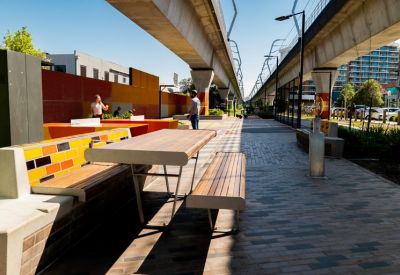 Public communal area with colorful tiled benches and wooden picnic tables.