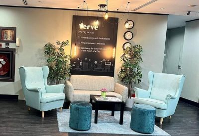 Stylish breakout area with pastel blue armchairs, a cream sofa, and decorative wall art.