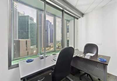 Private office suite with an L-shaped desk and views of city skyscrapers.