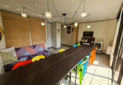 Colorful communal area with a long table and pendant lights.