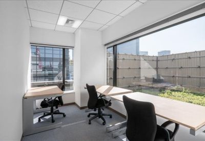 Private windowed office suite with three desks and ergonomic chairs.