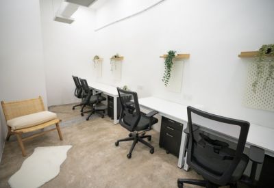 Bright open-plan office area with several black ergonomic chairs and white workstations.