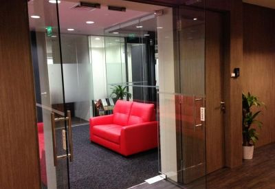 Glass-walled entrance to a reception area with a bright red leather sofa.