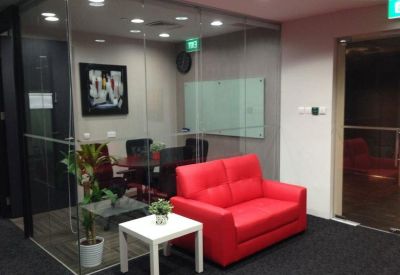 Glass-enclosed private meeting room with a red sofa and a white side table.