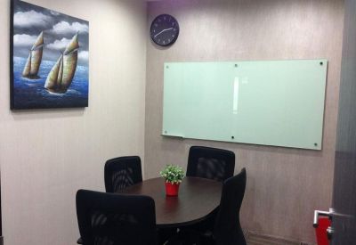 Small meeting room with a round table, four black chairs, and a glass whiteboard.