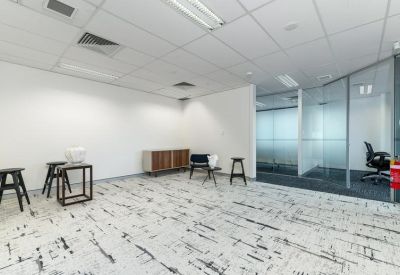 Casual breakout space with high stools, a wooden sideboard, and glass-walled offices.