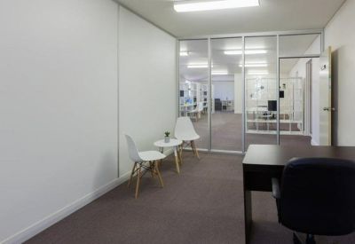Private office space with a dark desk, two guest chairs, and glass partition walls.