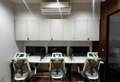 Bright three-person workstation area with ergonomic chairs and white overhead cabinets.