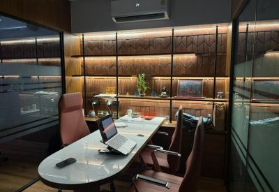 Small meeting room with an oval white table, brown leather chairs, and warm backlit shelving.