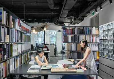 Material library and communal work table surrounded by floor-to-ceiling bookshelves.