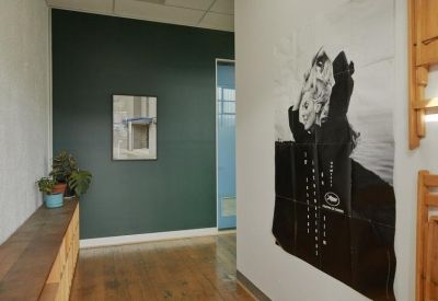 Entryway with a dark green feature wall, wooden flooring, and large wall art.