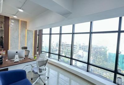 Sun-drenched private office with floor-to-ceiling windows showcasing a city view.