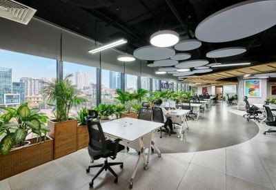 Bright open-plan workspace with potted plants and city views through large windows.