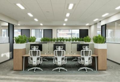 Modern open-plan office with ergonomic white chairs and integrated desk plants.
