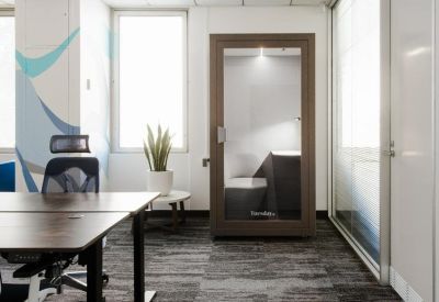 Modern office corner featuring a private phone booth and a standing desk setup.