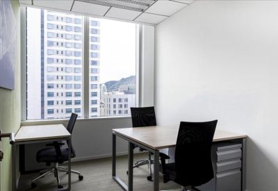 Bright open-plan workspace with white desks and black ergonomic chairs.
