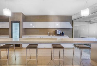 Modern communal kitchen and breakout area with a long breakfast bar and stools.