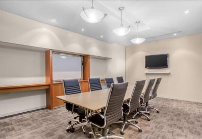 Spacious boardroom with a long table, ergonomic chairs, and modern pendant lighting.