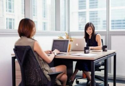 Two-person private office suite with large windows and wooden desks.