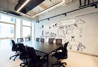 Bright conference room with a large black table and playful wall illustrations.