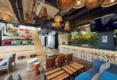 Social hub featuring tiered stadium seating with colorful cushions and hanging basket lamps.